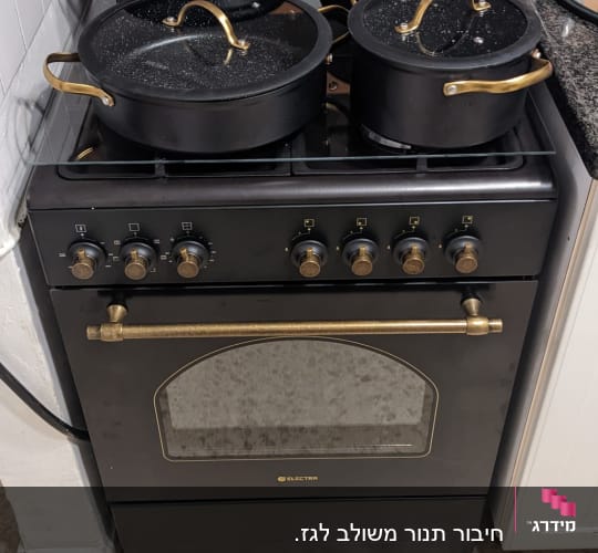 תנור גז שחור עם סירים שחורים ומכסים שקופים